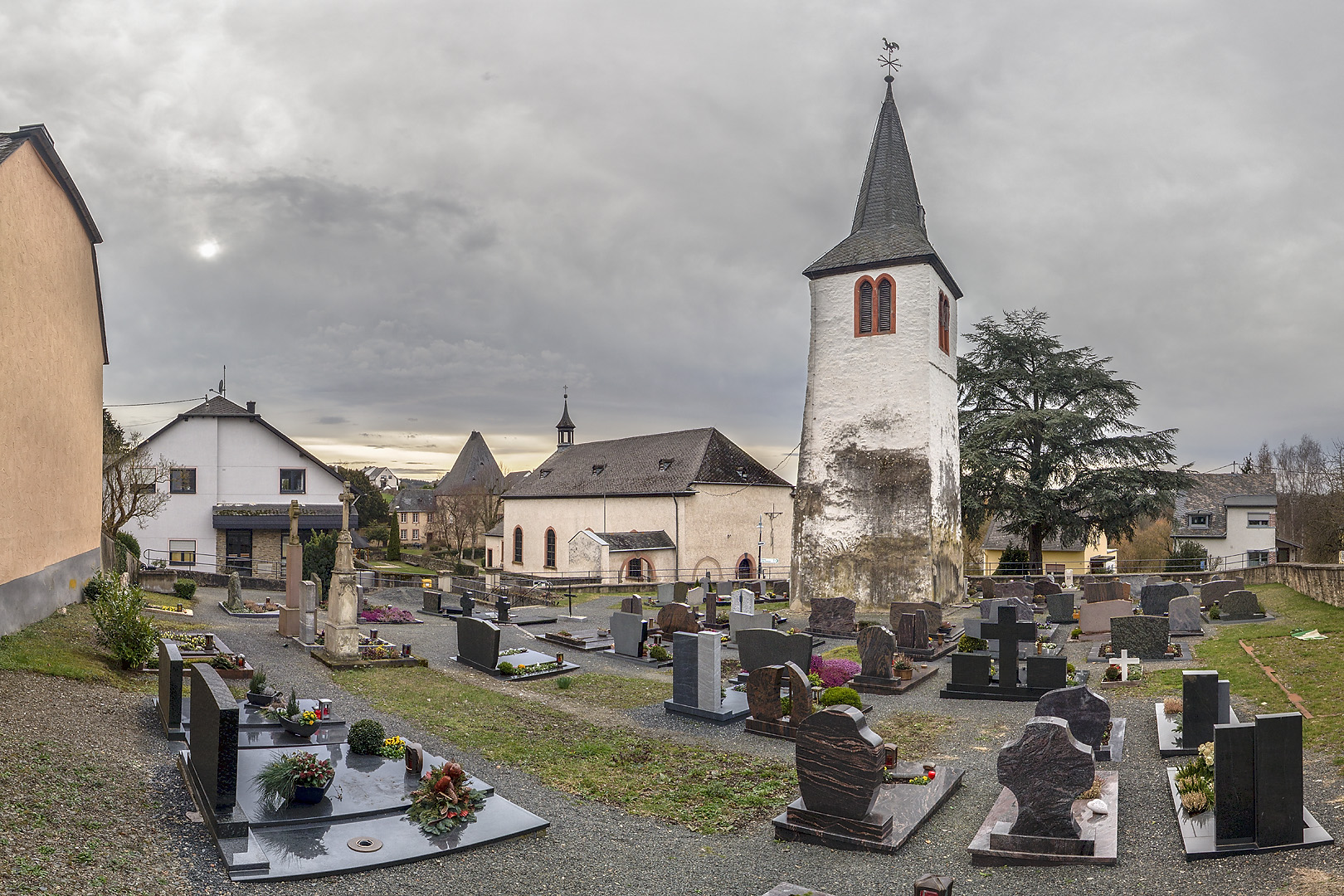 Rechts freistehender Kirchturm in Friedhof in der Mitte die Kirche und dahinter die 'Irscher Burg'